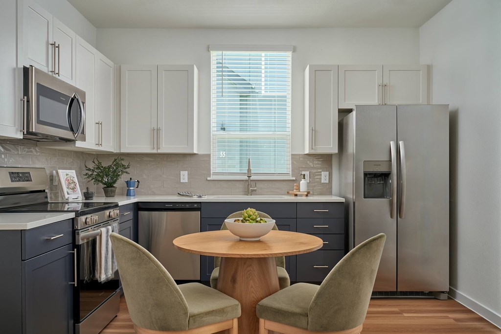 A kitchen with a table and two chairs.