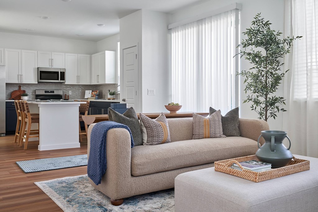 A living room with a couch, a chair, a table, and a potted plant.