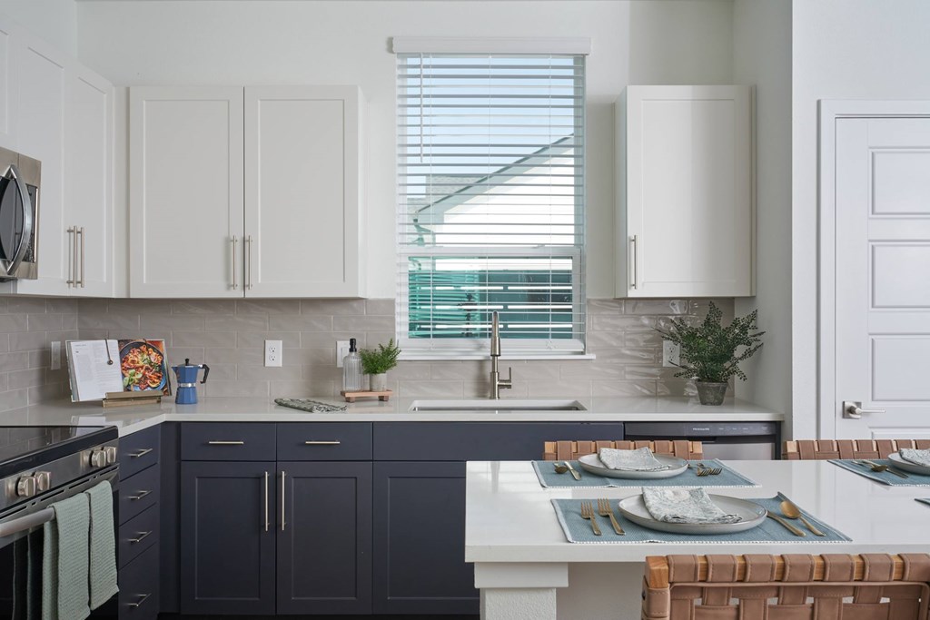 A kitchen with a white countertop and dark blue cabinets.