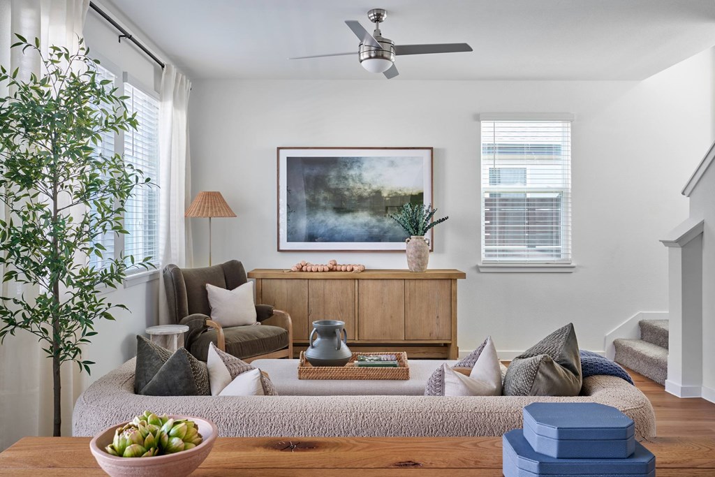 A living room with a couch, a chair, a table with a bowl of fruit, and a painting on the wall.