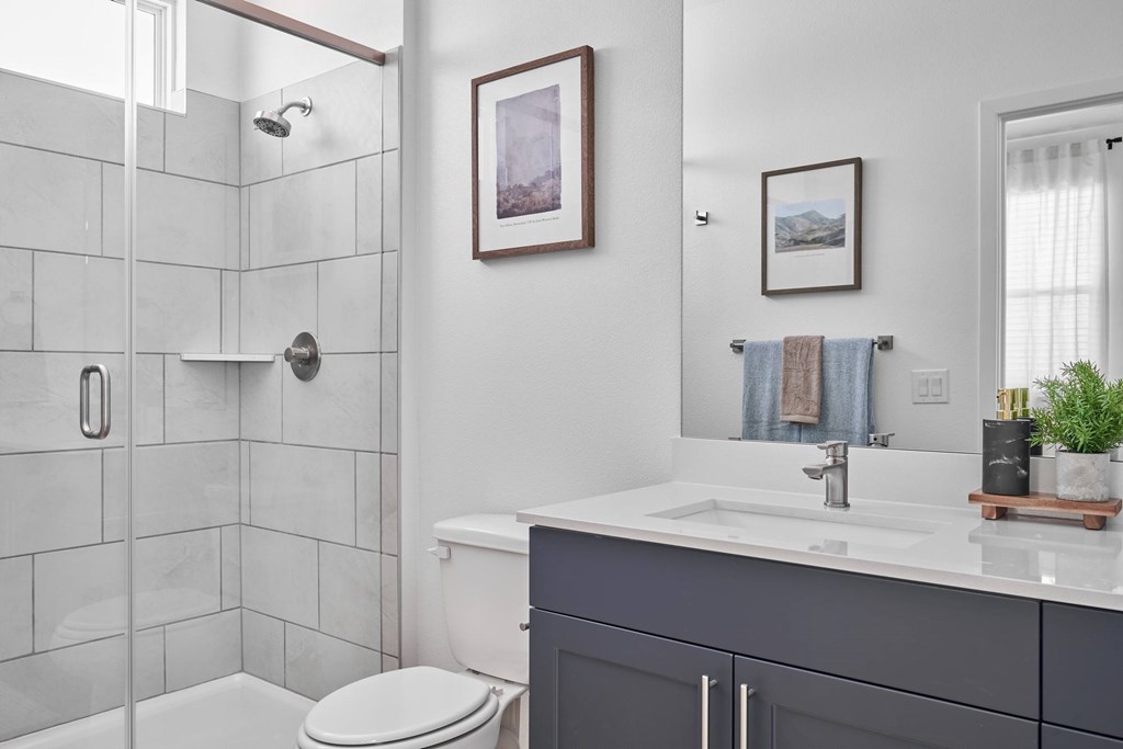 A bathroom with a white toilet, a white sink, and a shower with a glass door.