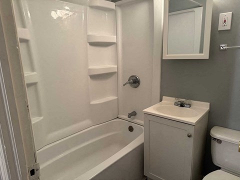 A white bathroom with a toilet, sink, and bathtub.