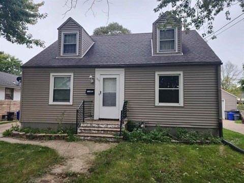 A small house with a white door and two windows.