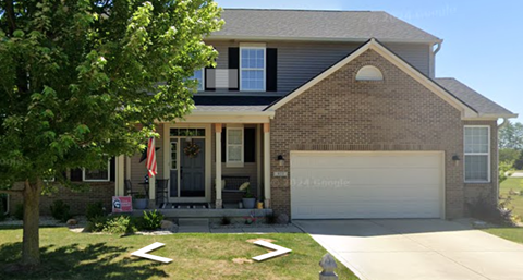 A house with a garage and a tree in front.