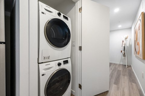 A white washing machine and dryer stacked on top of each other in a small laundry room.