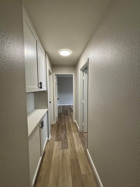 A long hallway with white walls and wood flooring.