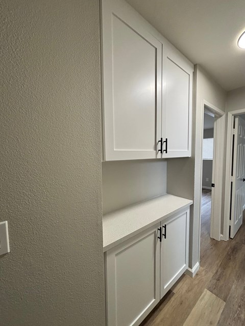 A kitchen with white cabinets and a light brown floor.