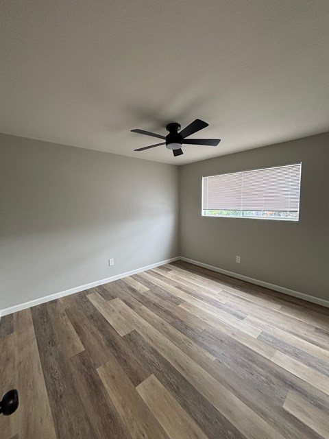 A room with a ceiling fan and a window with blinds.