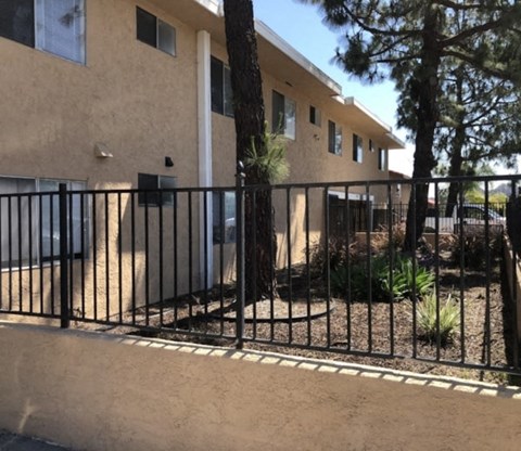 A house with a black fence and a tree in front.