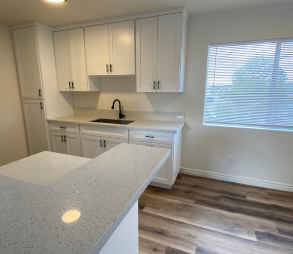 A kitchen with white cabinets and a granite countertop.