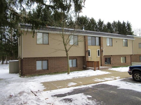 A building with a brown and beige exterior is surrounded by snow.