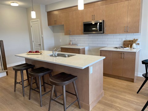 A kitchen with a white counter top and brown bar stools.