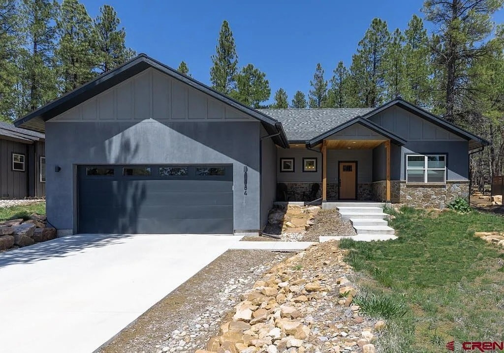A modern house with a grey garage door and a stone pathway leading to the entrance.