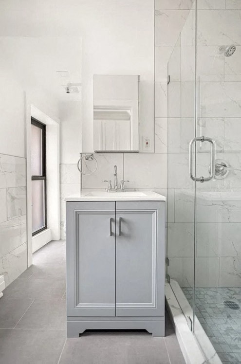 A white cabinet with a sink is in a bathroom.