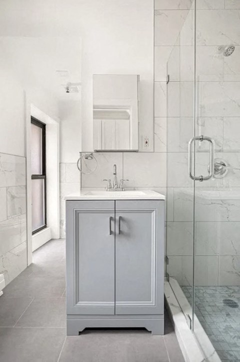 A white cabinet with a sink is in a bathroom.