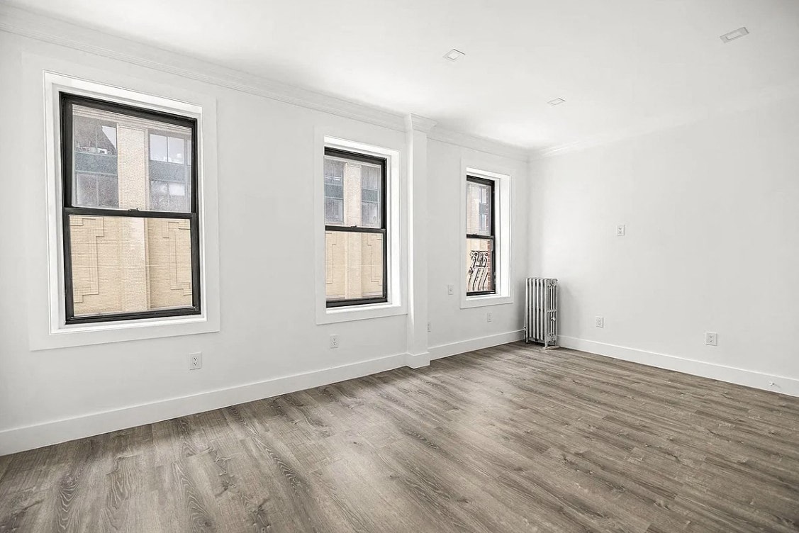 A room with two windows and a radiator on the wall.