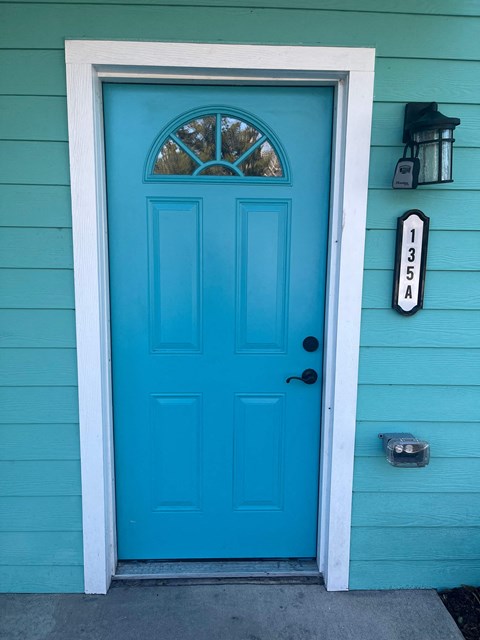 A blue door with a white frame and a mailbox on the wall.