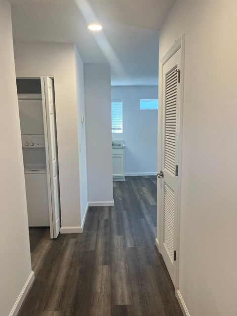A hallway with a white door and a white wall.
