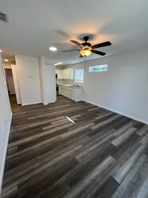 A room with a ceiling fan and wooden flooring.