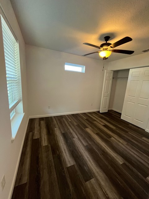 A room with a ceiling fan and wooden flooring.