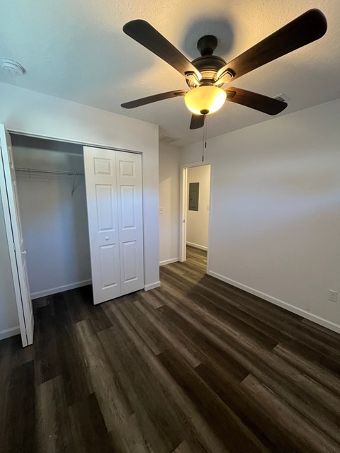 A room with a ceiling fan and wood flooring.