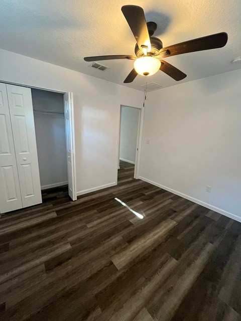 A room with a ceiling fan and wooden flooring.