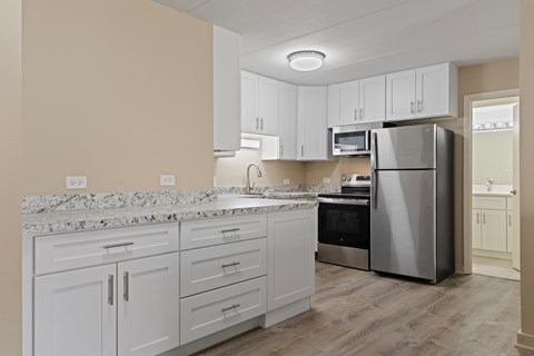A kitchen with white cabinets and a marble countertop.