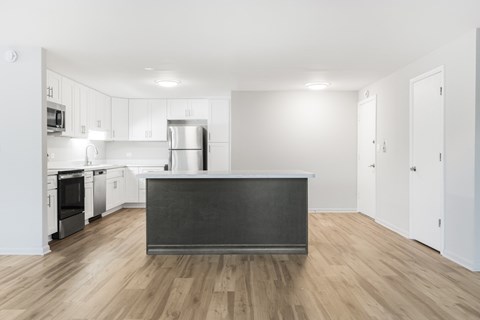 A kitchen with a black countertop and wooden floors.