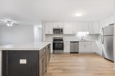 A modern kitchen with stainless steel appliances and wooden floors.