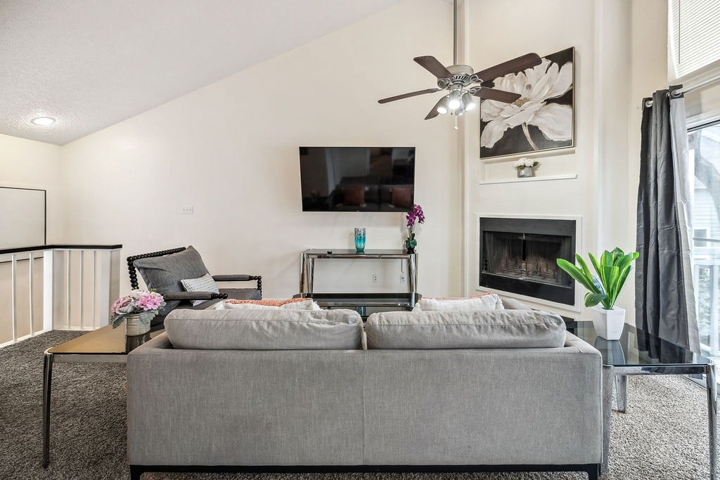A living room with a grey couch and a flat screen TV mounted on the wall.