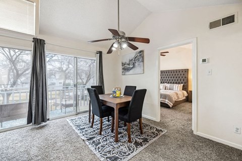 A dining room with a table and chairs and a ceiling fan.