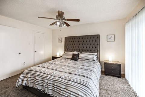 A bedroom with a large bed and a ceiling fan.