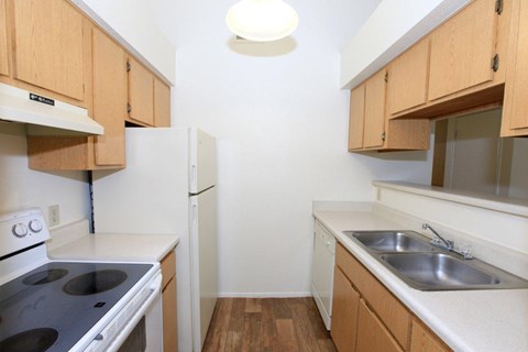 A kitchen with wooden cabinets and a white stove top oven.