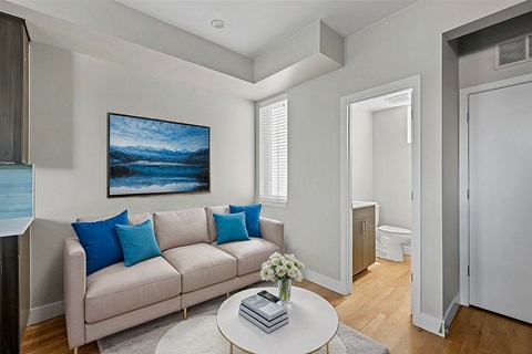 A living room with a couch, a coffee table, and a painting on the wall.