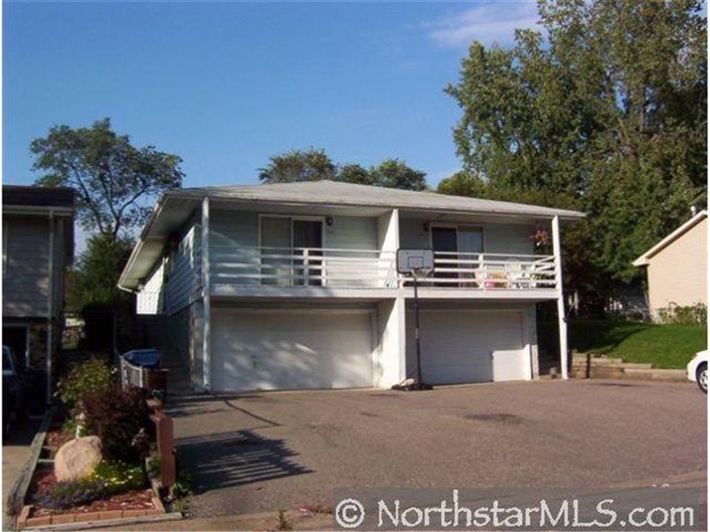 A two-story house with a garage is surrounded by trees.