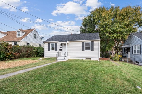 A small house with a grey roof and a white fence.