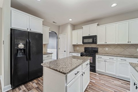 A kitchen with black and white cabinets and a granite countertop.