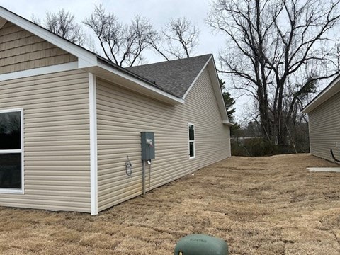 A small house with a brown roof and a grey garage door.