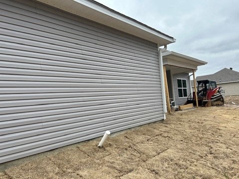 A house with a grey siding and a red vehicle in front.
