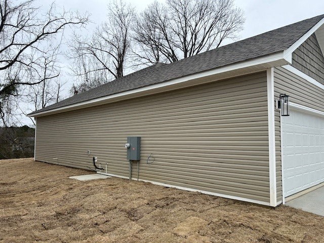 A garage with a grey roof and a white door is situated in a field.