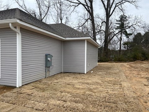 A metal garage door is closed and the garage is white.