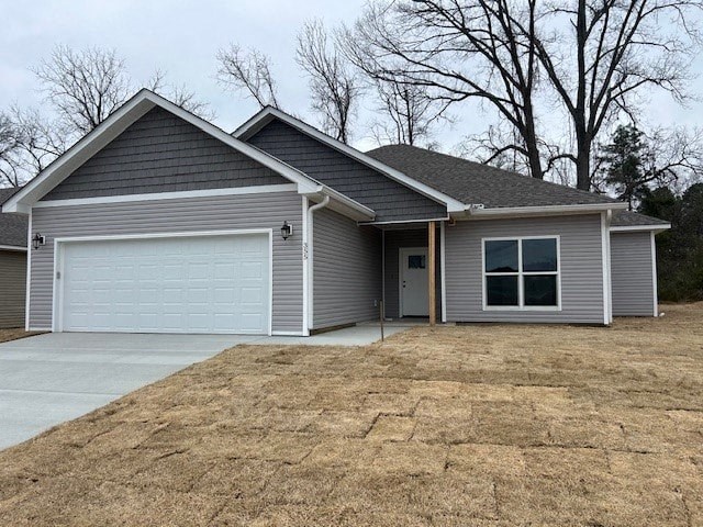 A grey house with a white garage door and a brown driveway.