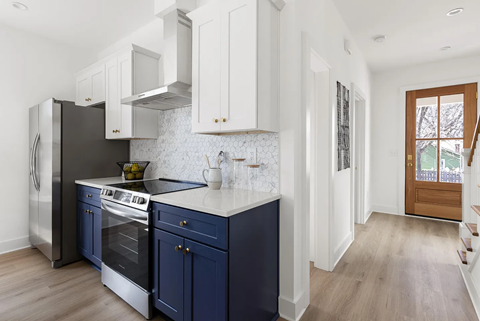 A kitchen with dark blue cabinets and a stainless steel refrigerator.