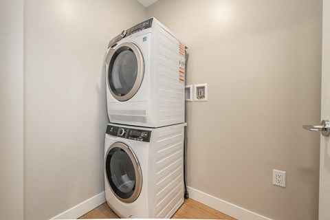Two white front load washing machines stacked on top of each other in a laundry room.