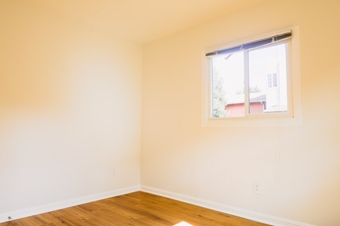 A room with a window and wooden floors.