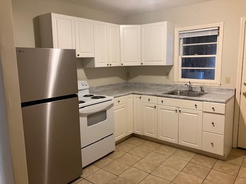 A kitchen with white cabinets and a stainless steel refrigerator.