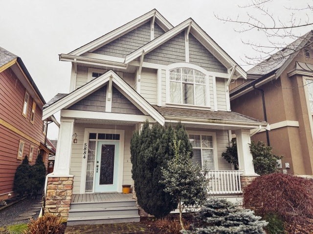 A house with a grey roof and a white door is surrounded by greenery.