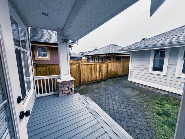 A wooden deck with a white railing and a stone pillar.