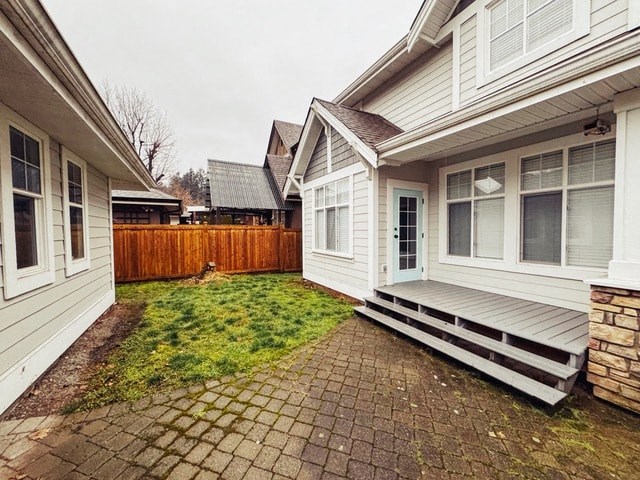 A backyard with a wooden fence and a brick patio.