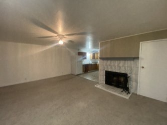 A living room with a fireplace and a ceiling fan.